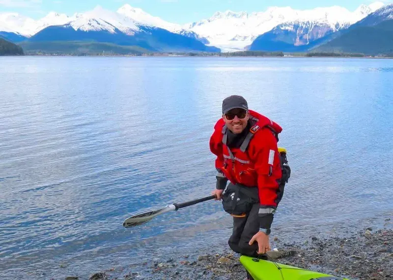 Kayaker in a dry suit paddling the Mendenhall Wetlands with the glacier visible on a Juneau sea kayak tour