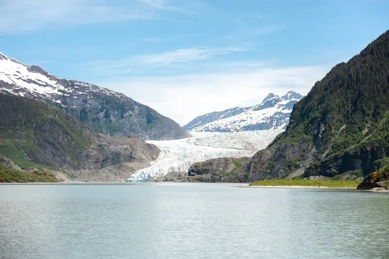 Humpback whale fluke rising in front of snow-capped peaks on a Juneau whale watching and Mendenhall Glacier tour
