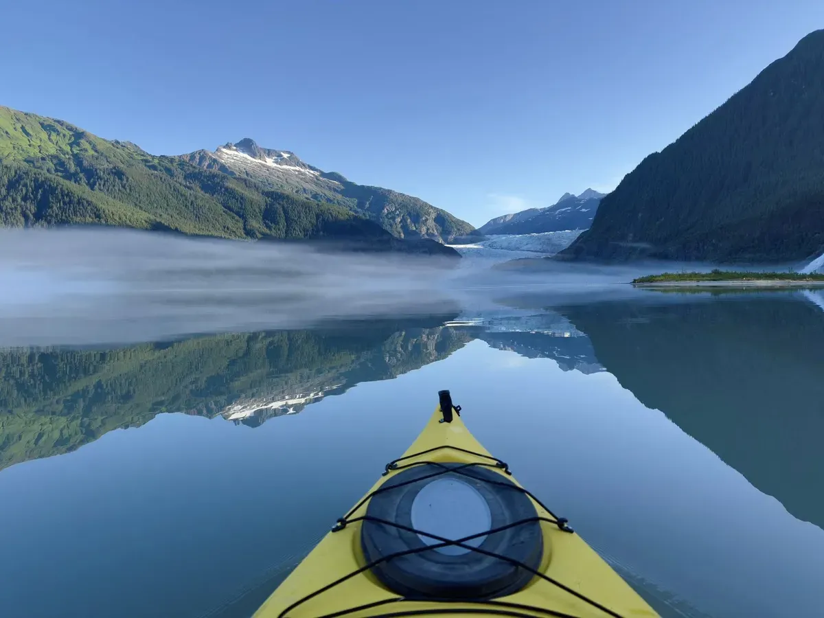 Paddlers crossing iceberg-dotted water toward the blue ice face on the Mendenhall Lake canoe tour near Juneau, Alaska