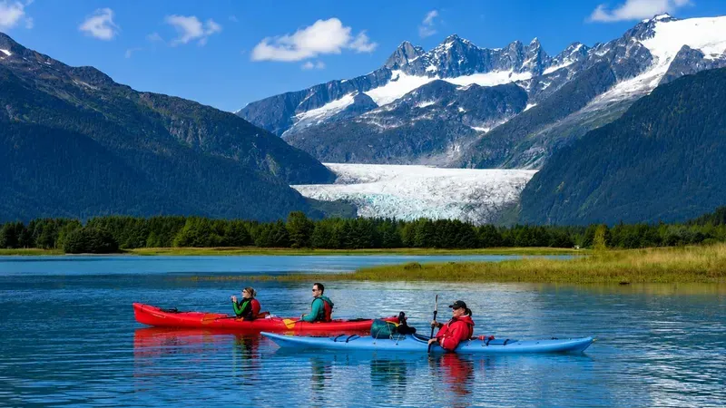 Canoe group paddling past icebergs toward the ice face on a Mendenhall Lake canoe tour to Mendenhall Glacier